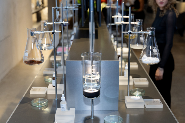 Steffi Bühlmaier Set Design. Skincare brand The Ordinary’s temporary showroom at the Highsnobiety Store in Berlin. Products are displayed in laboratory vessels on a tiled counter with steel tabletop.